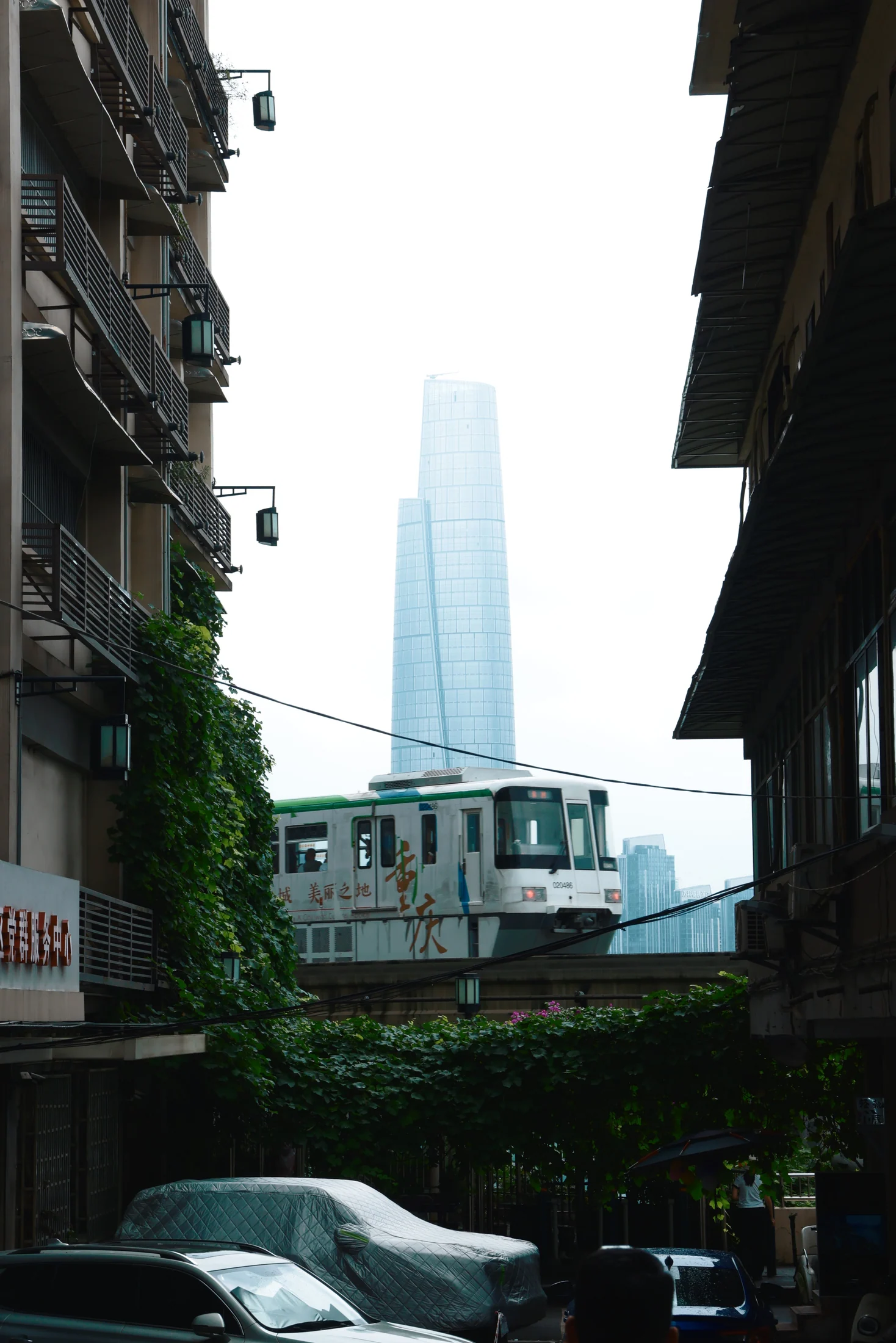 列车穿过旧楼之间，远处可见现代高楼